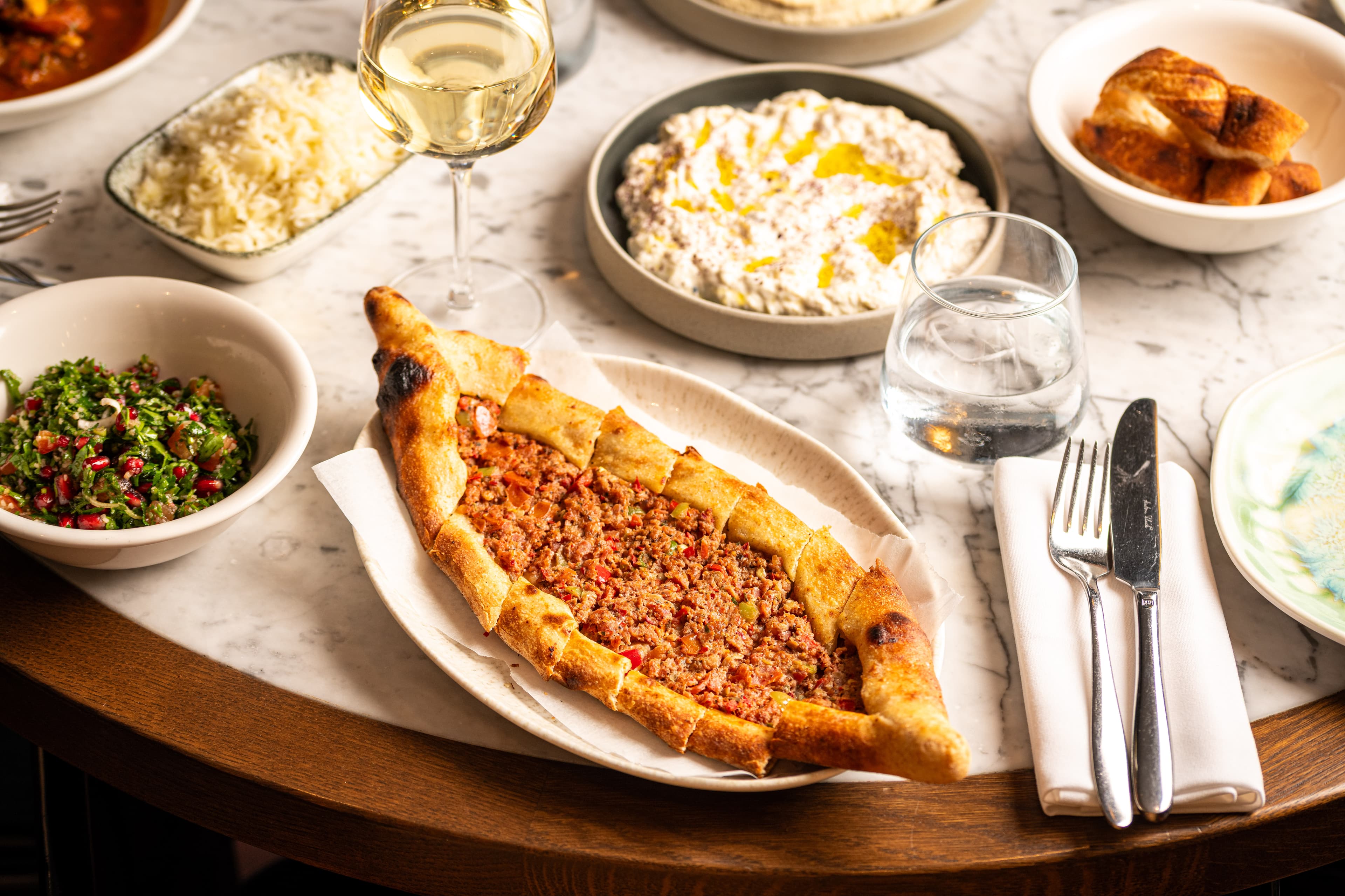 A freshly baked pide served with Mediterranean dips and salad