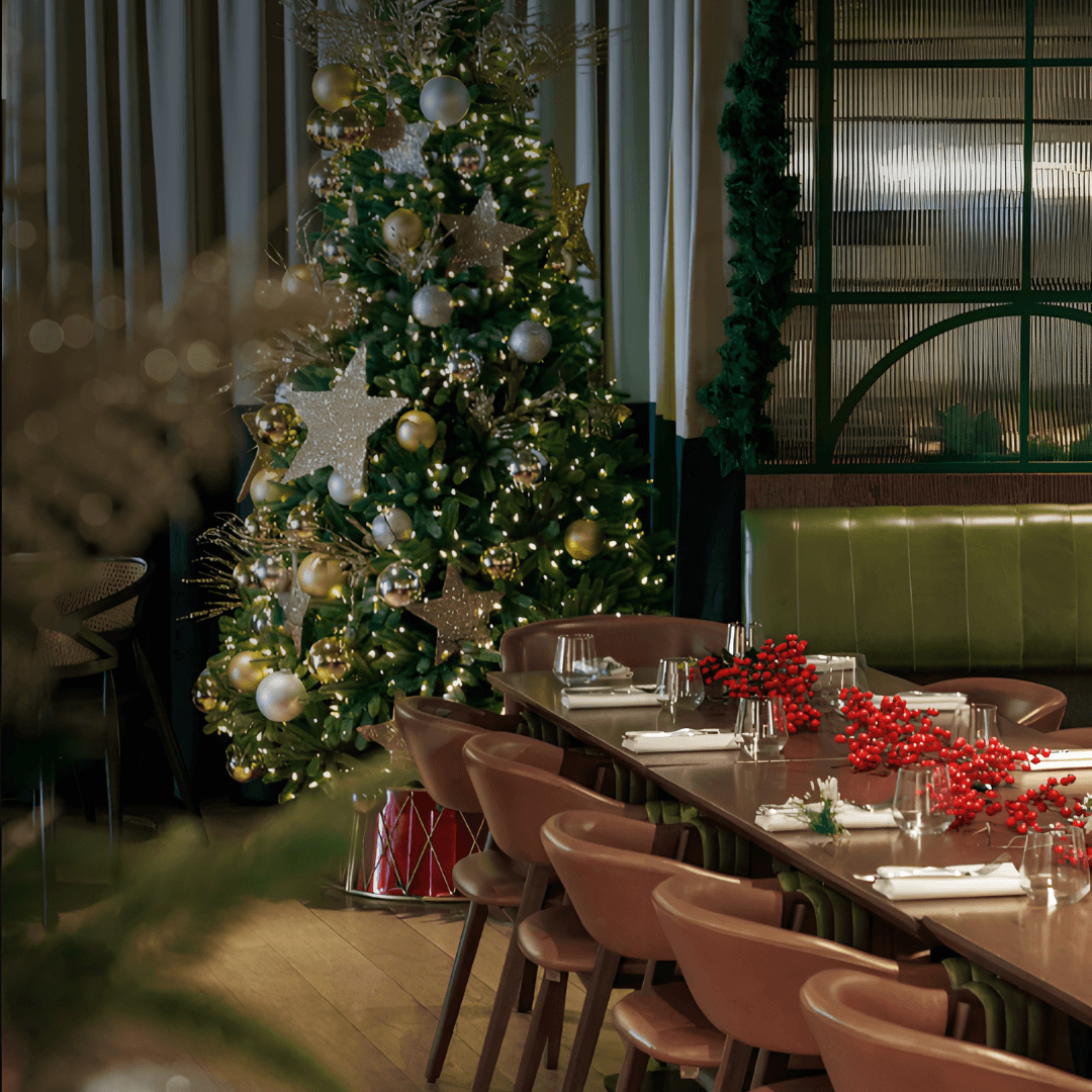 Decorated Christmas tree beside a table set with red berries at Olea Social