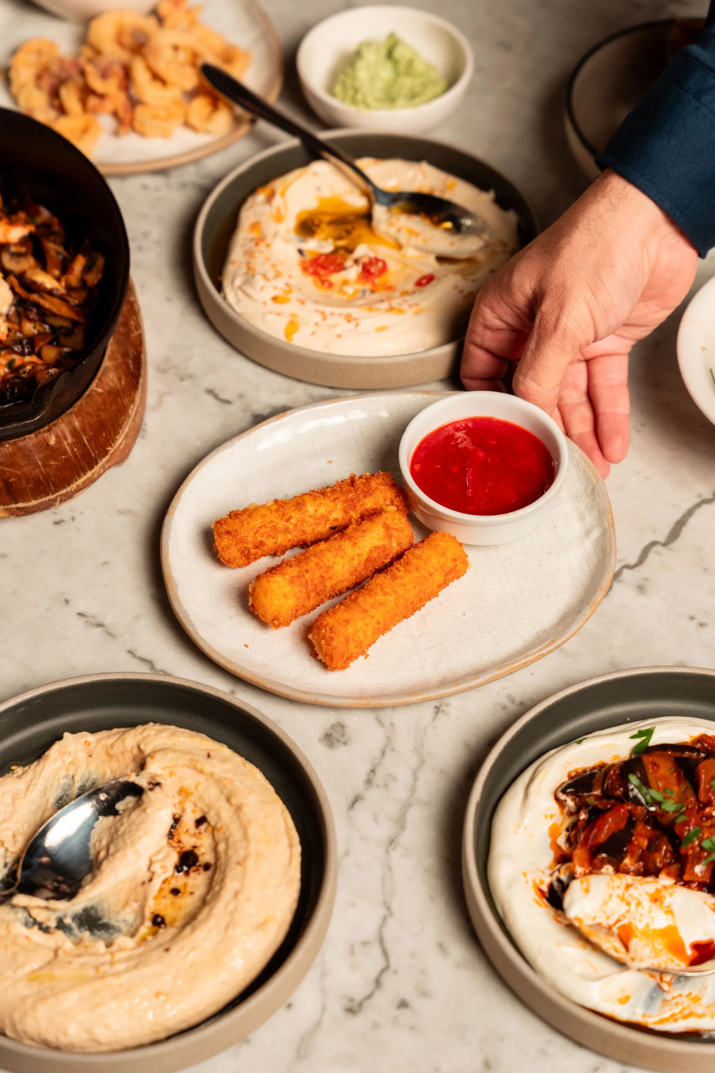 Overhead view of a marble table spread with hummus, croquetas, dips and meze at Olea Social